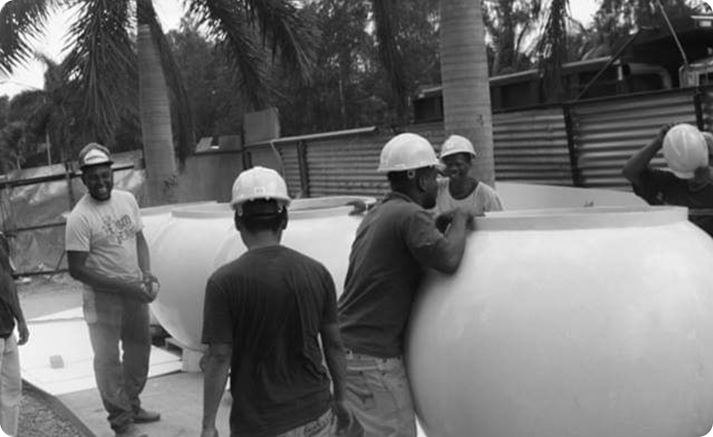 Workers handling large custom concrete furniture element during installation